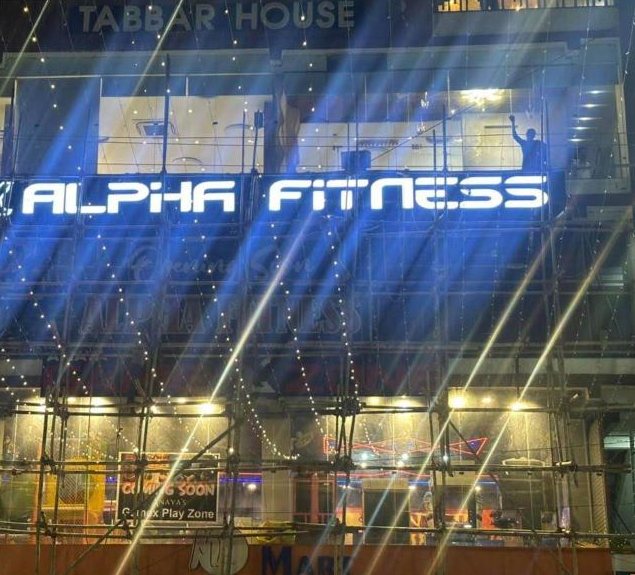 Alpha Fitness wordmark lit up across Gaurav Tower at night