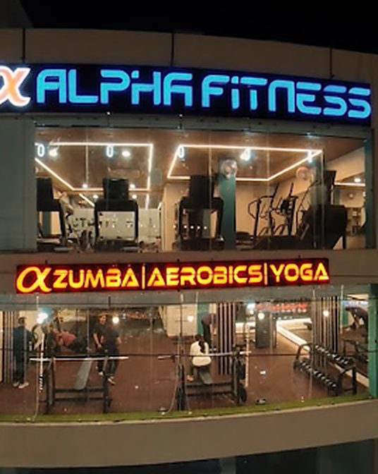 Lit Alpha Fitness sign above the Zumba, Aerobics, Yoga sign at night