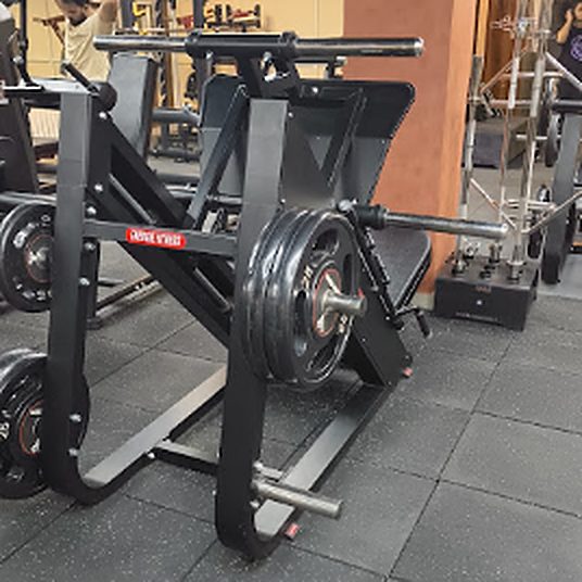Black plate-loaded leg press machine on the strength floor